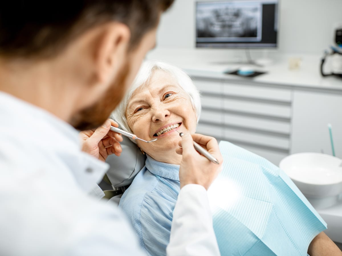 Elderly woman receiving dentures from dentist